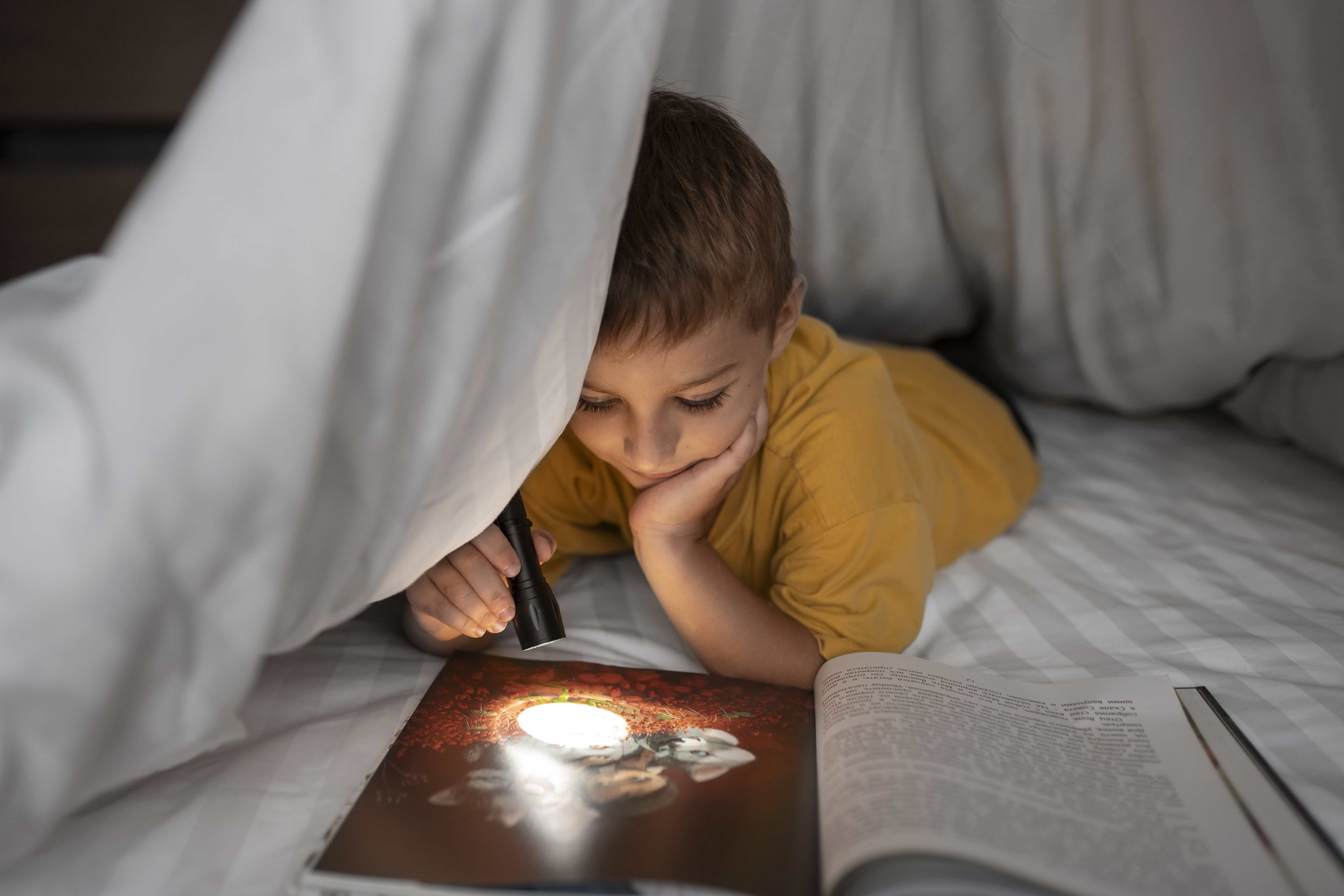 front-view-kid-reading-magazine-with-flashlight.jpg